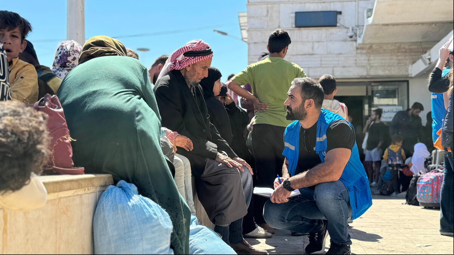A UNHCR staff member talks to families arriving from Lebanon at the Jdaidet Yabous border crossing in Syria. Following the intensification of Israeli bombings in Lebanon since 23 September 2024, thousands of Syrian and Lebanese people have crossed into Syria, fleeing the violence. UNHCR is scaling up for the growing number of displaced. Syria. Thousands of people fleeing Israeli airstrikes arrive from Lebanon
