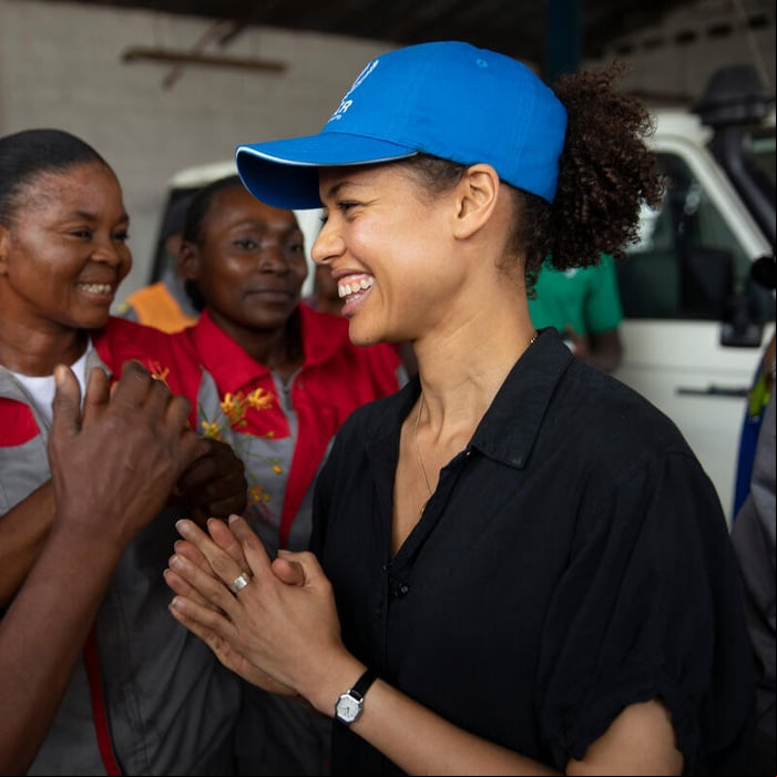 Sonriente, una mujer afrobritánica charla con un grupo de mujeres congoleñas.