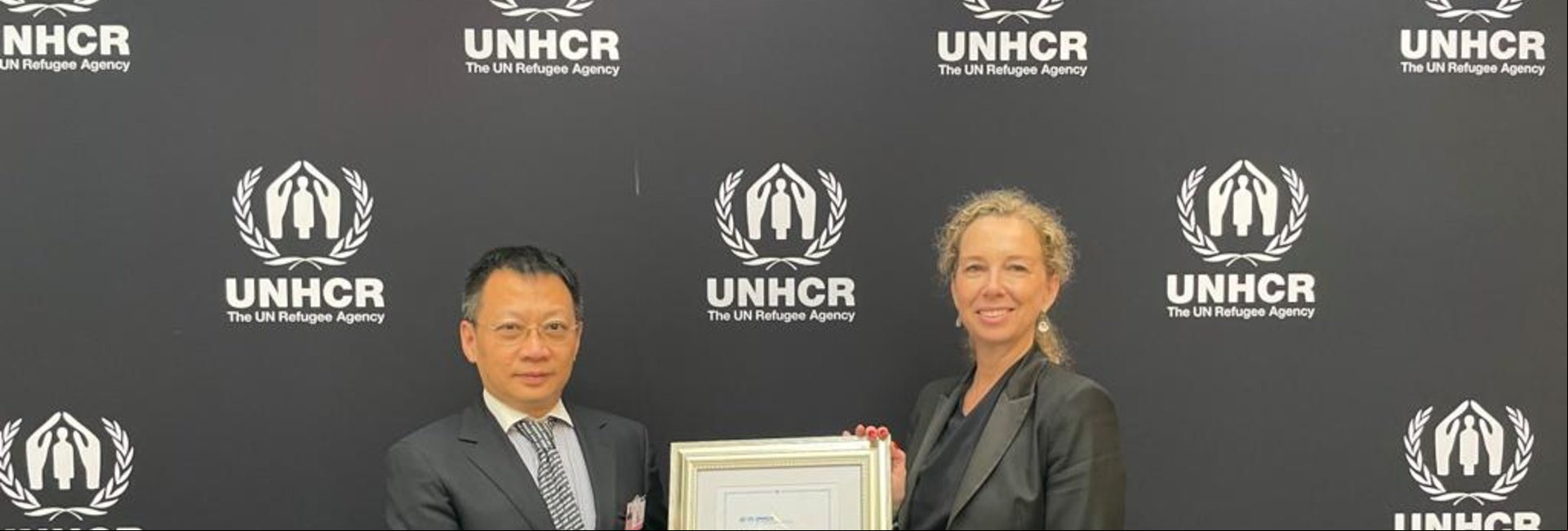 Un hombre chino recibe un reconocimiento de una mujer caucásica
