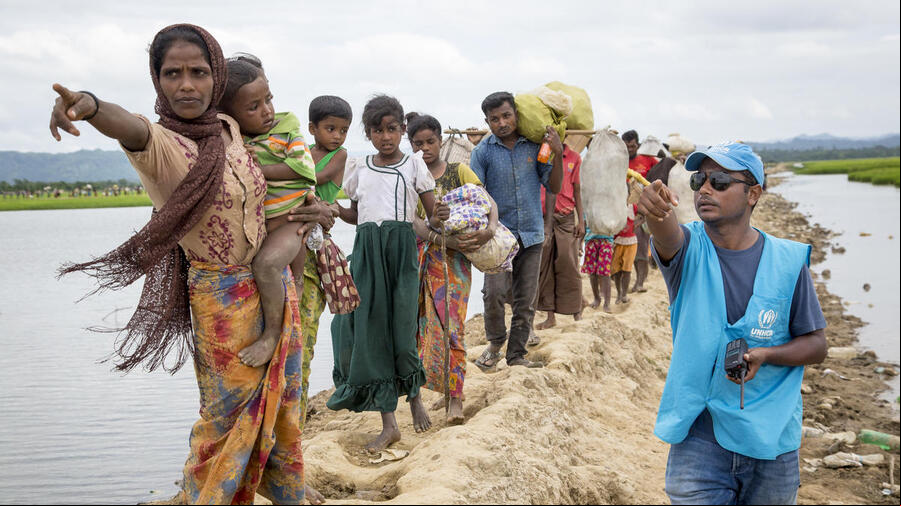 Rohingya arrivals at transit centre Una trabajadora de ACNUR le indica a un grupo de personas rohingyas refugiadas dónde se encuentra el centro de tránsito.